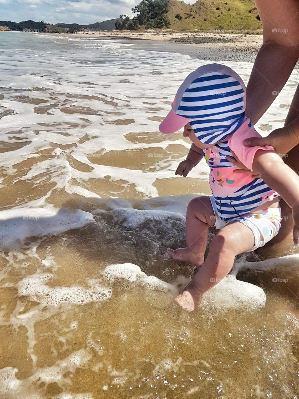 Baby Girl and Mother playing in water at the beach