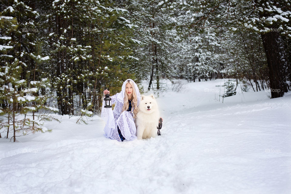 Woman with dog sitting on snowy landscape