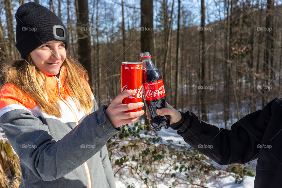 girl and boy clink bottles of Coke