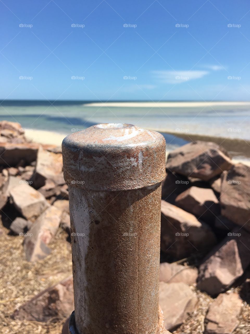 View from Rock Jetty Rusty iron post foreground, ocean horizon background 