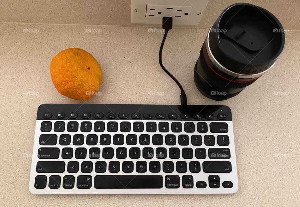 Still life , with keyboard , coffee in a lens cup, and a tangerine.