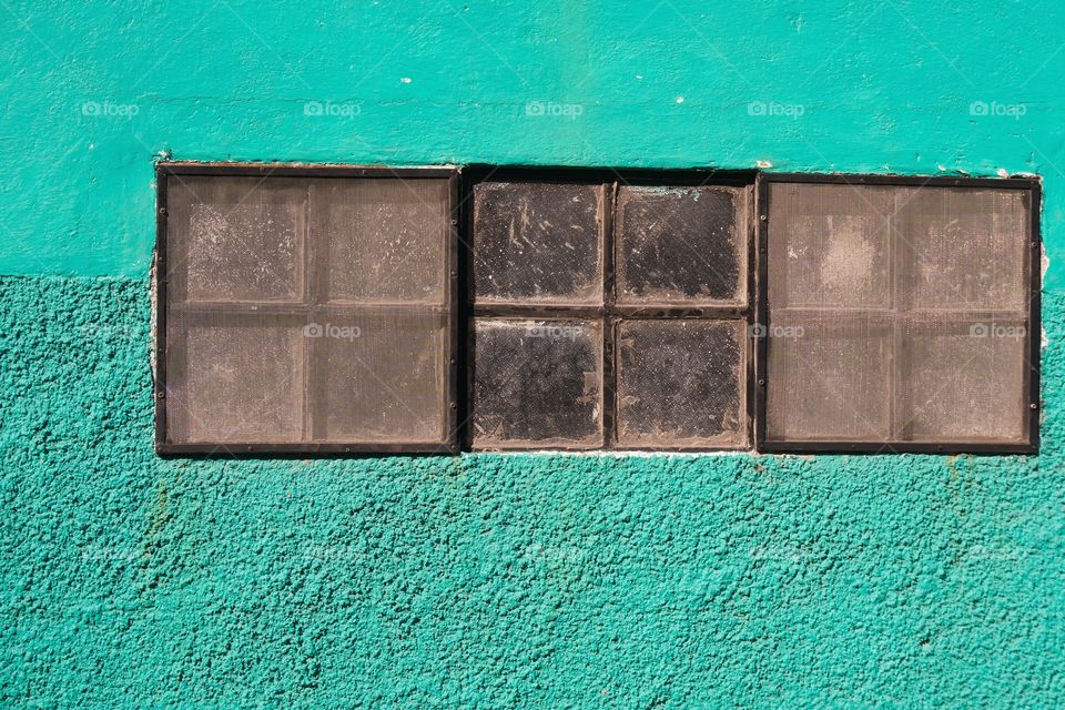 Windows and screens on a green stucco wall in San Miguel de Allende, Mexico