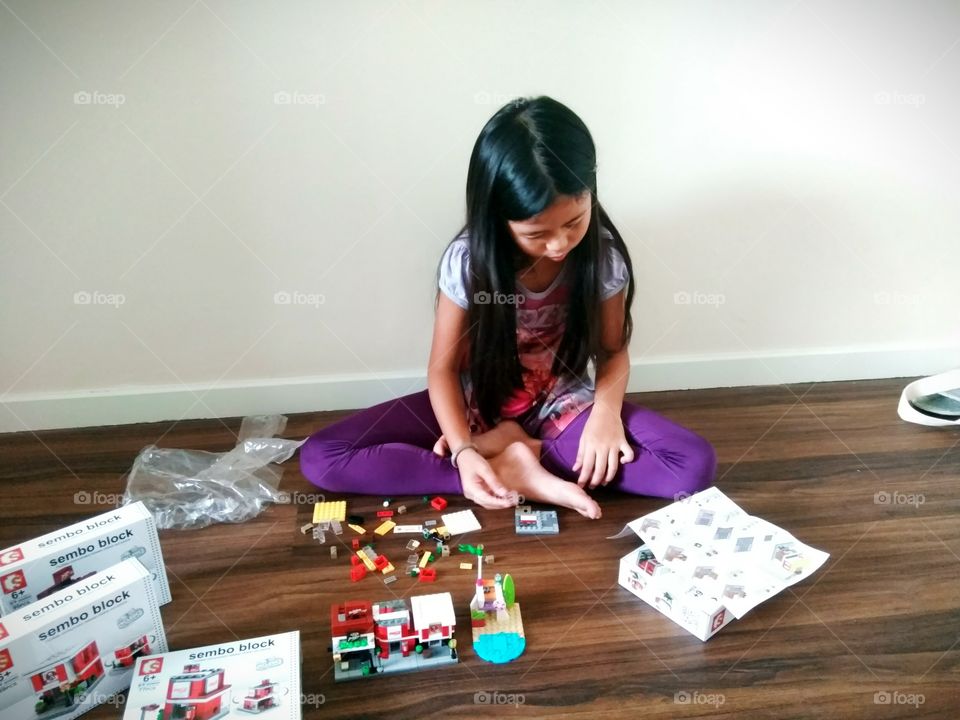 little girl sitting on the floor playing blocks