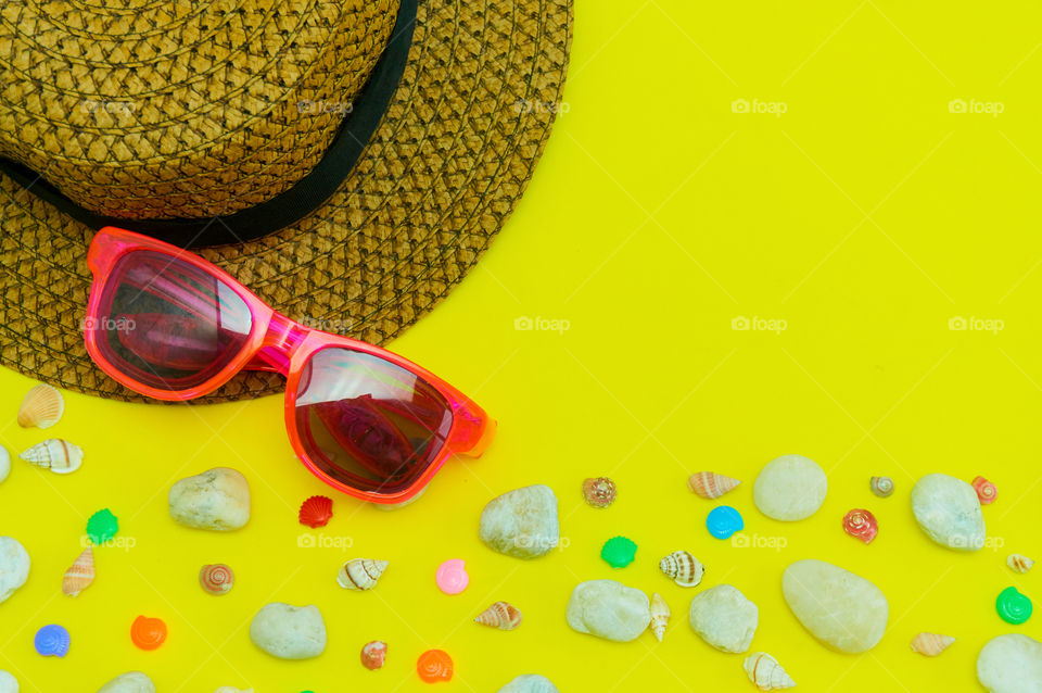 Summer concept with sunglasses, hat on yellow background 