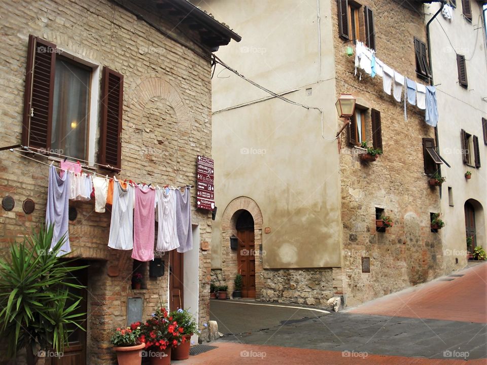 The unique and unforgettable charm of the Italian streets in a small town. Houses made of light stone, clothes hung, flowers in pots.