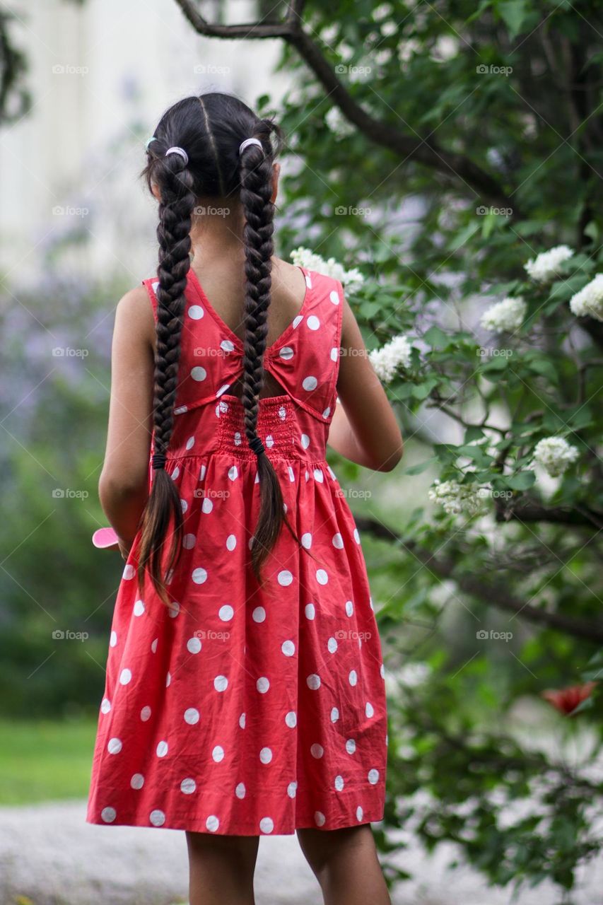 Girl with long braids in a red with white polka dots dress