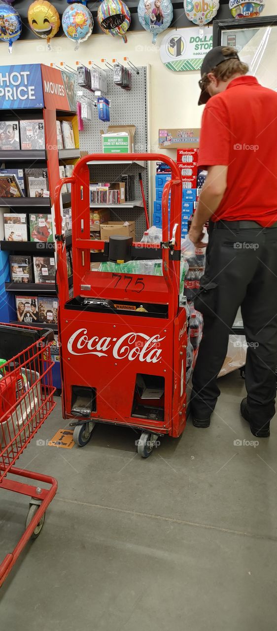 Red Coca-cola cart being unloaded by Coke employee