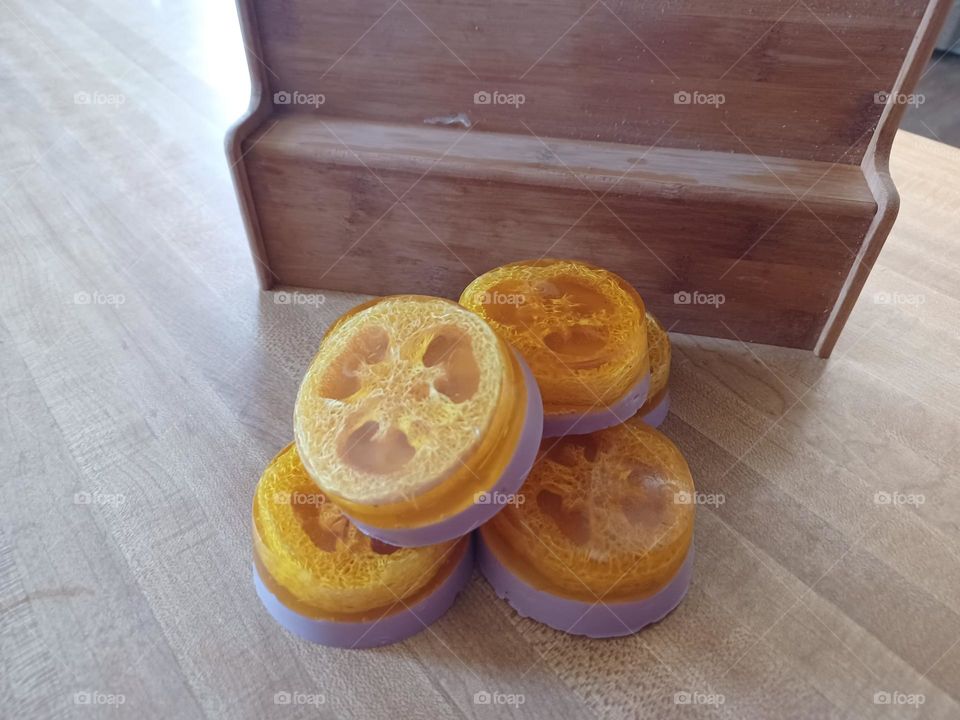 Handmade Circular Loofah Soap bars on a counter in front of a spice shelf rack