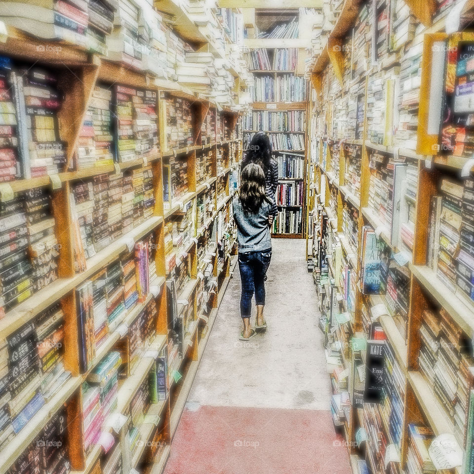Two girls walking through a bookstore.