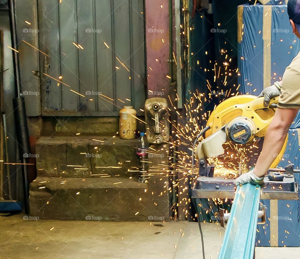 Sparks fly from a piece of steel while it is cut.