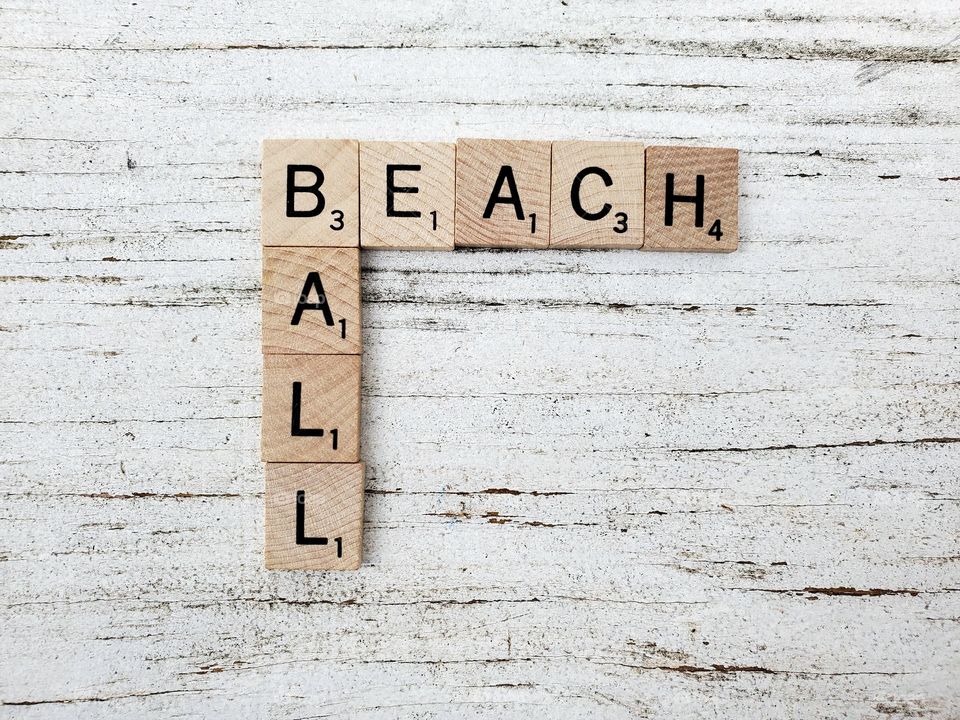 Beach ball wooden square word tiles on a rustic white background 