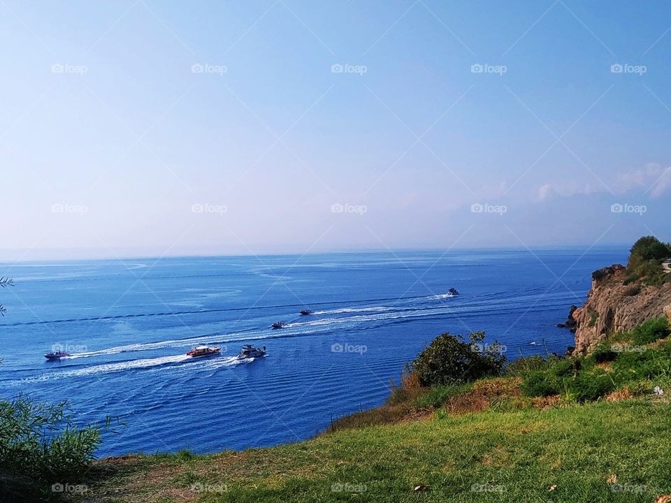 Many boats and ships floating on the sea by the beautiful cliff seashore with nature.