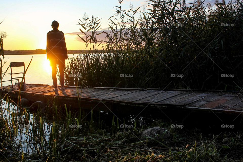 a girl stands on a log on a lake at dawn