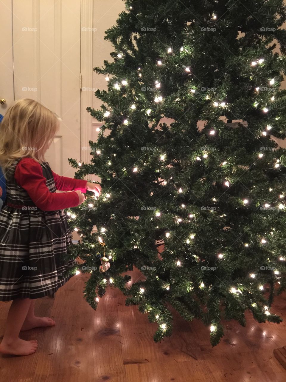 Toddler decorating Tree. Girl helps decorate Christmas tree