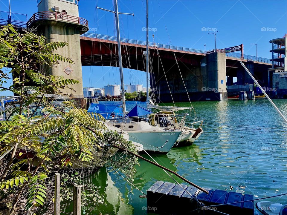 This is the “Pulaski Bridge” at “Newtown Creek” seen from the LIC shore. Two sailboats can also be seen on the waters of the “East River” on this lovely sunny and warm Indian summer day in early October 2023. Hypnotic Productions