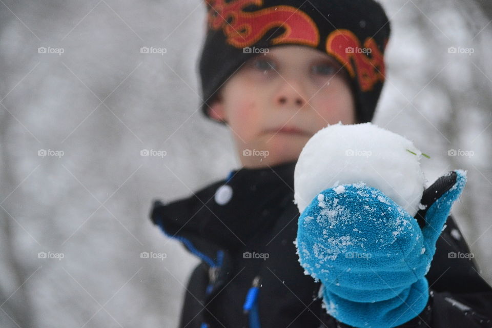 Little baby boy with snow ball