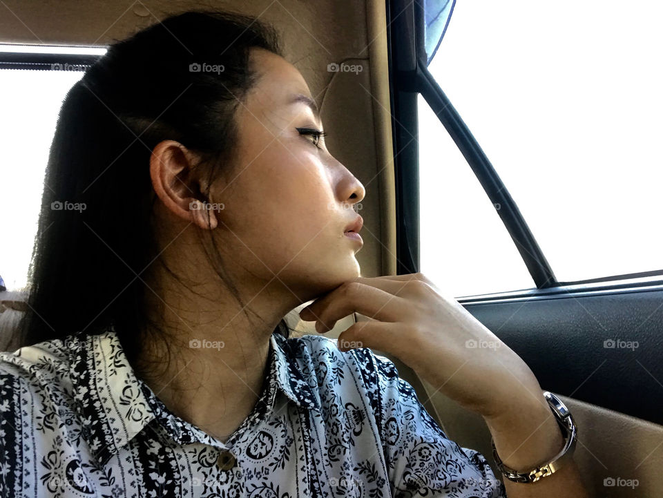 Side face of Thai woman while look around of of the car during heavy traffic in Thailand