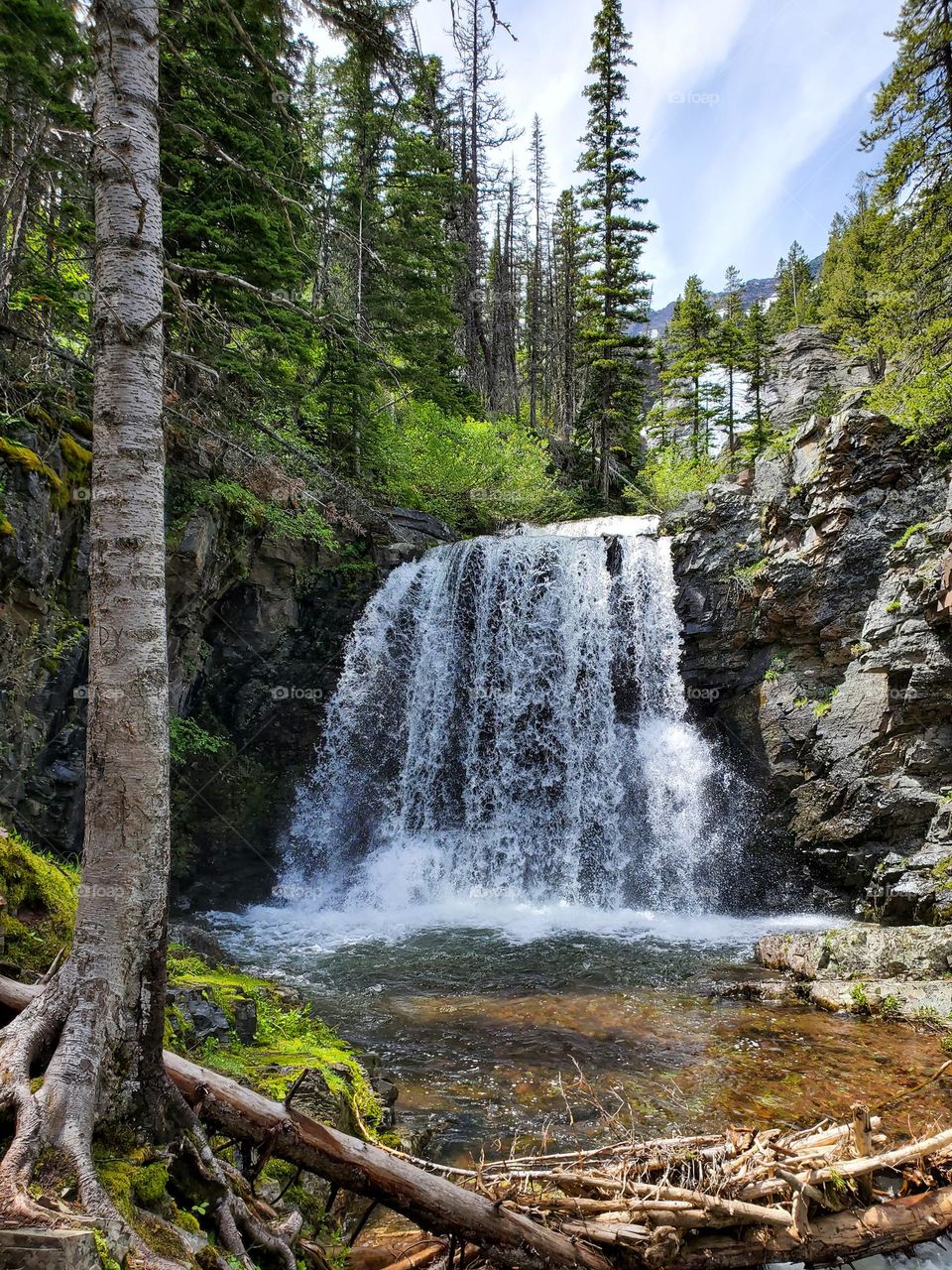 A clear cold pond results from a large waterfall as summer temperatures cause ice to melt at its glacial source