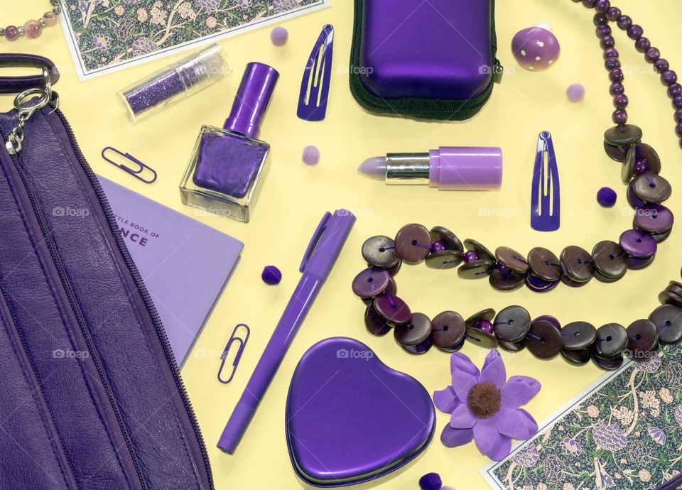 The purple contents of a purple handbag, spilled out over a yellow background 