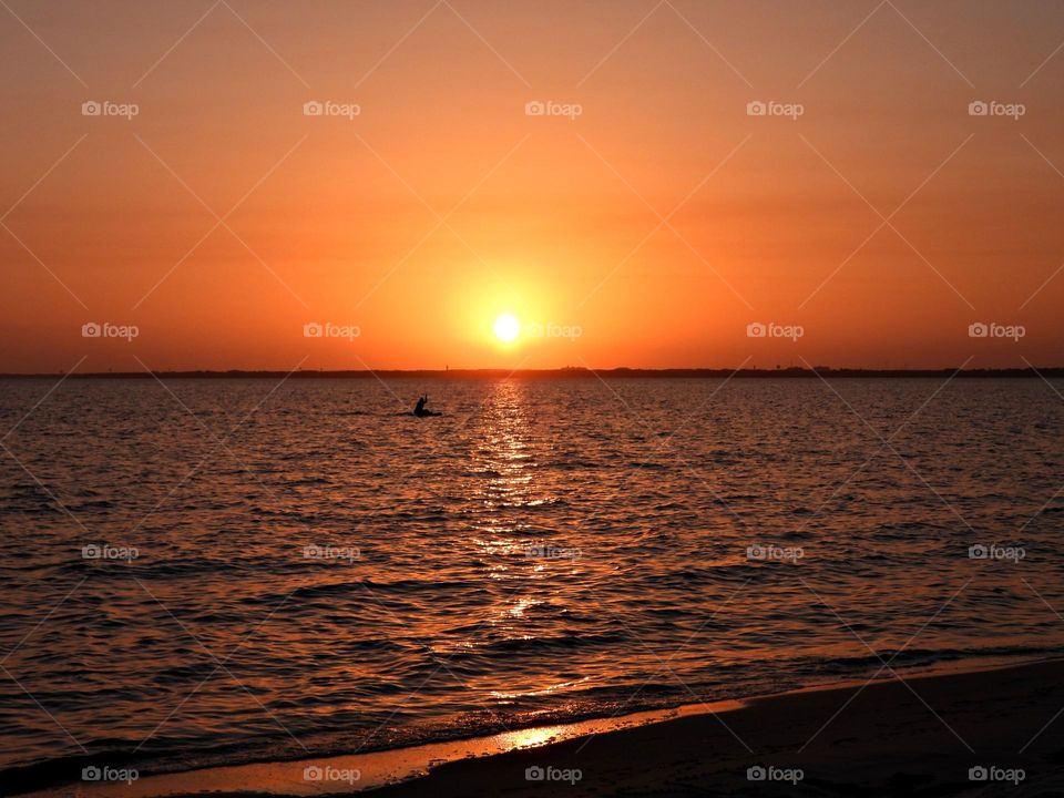 It was sunset. She watched from her kayak with an unwavering gaze, as a fiery orange orb of light slowly sank beneath the horizon combine for the perfect evening.