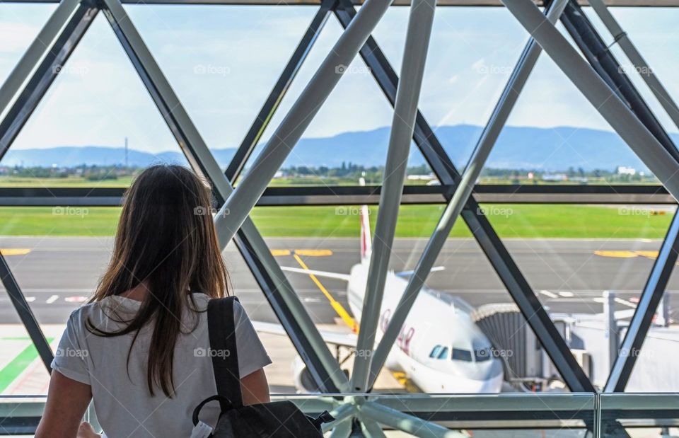 Rear view of woman looking out of the window at the airport