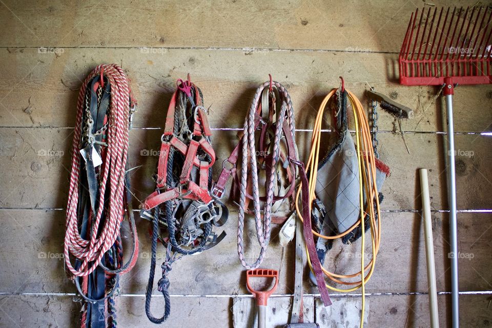 Horse-riding equipment and tools against the wall of an old wooden barn