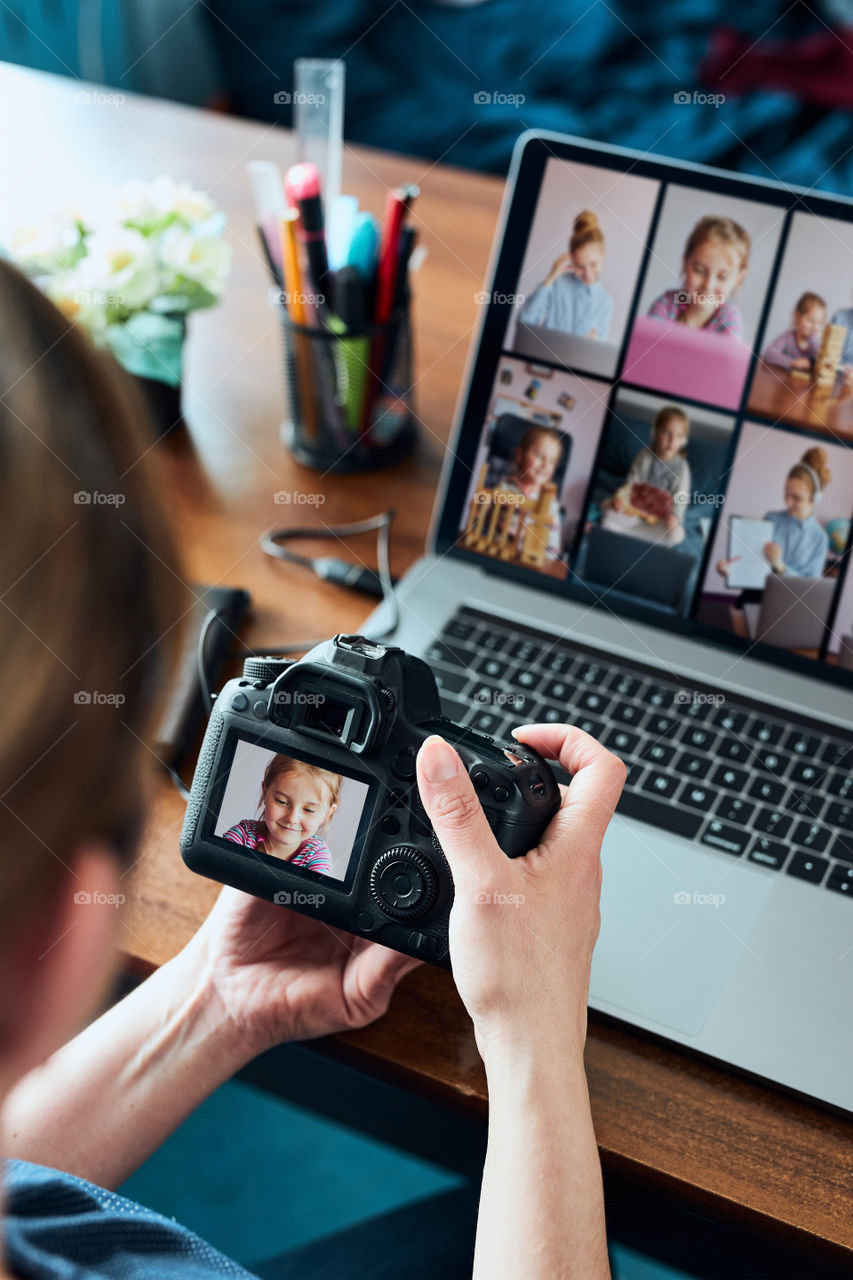 Female photographer working on photos on laptop and camera. Woman editing retouching browsing photos working as a freelancer sitting at desk