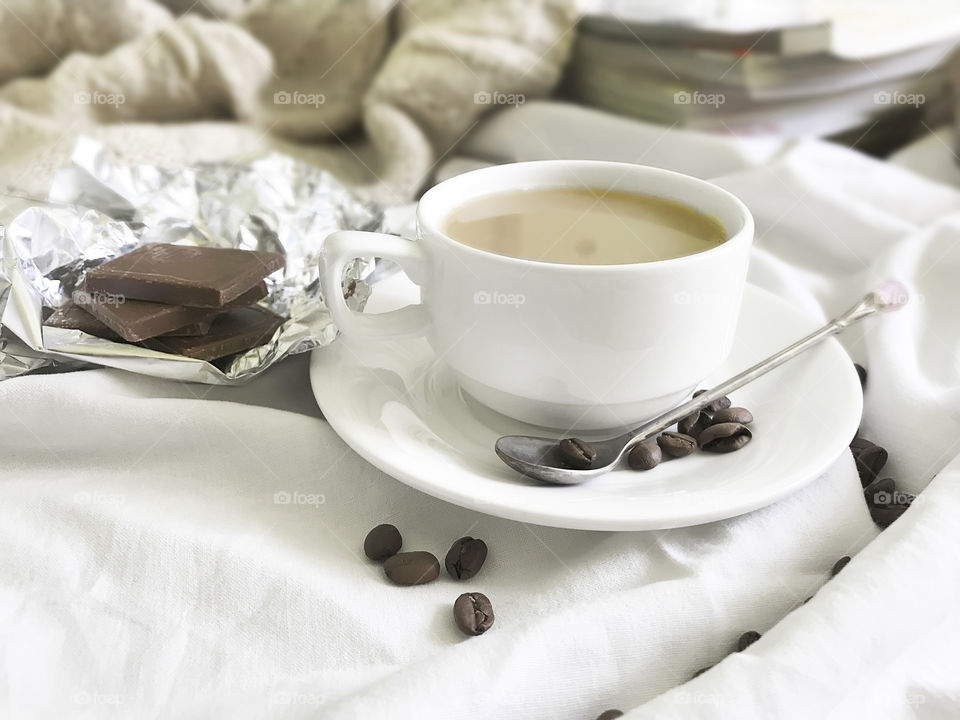 White coffee cup with chocolate in white bed 