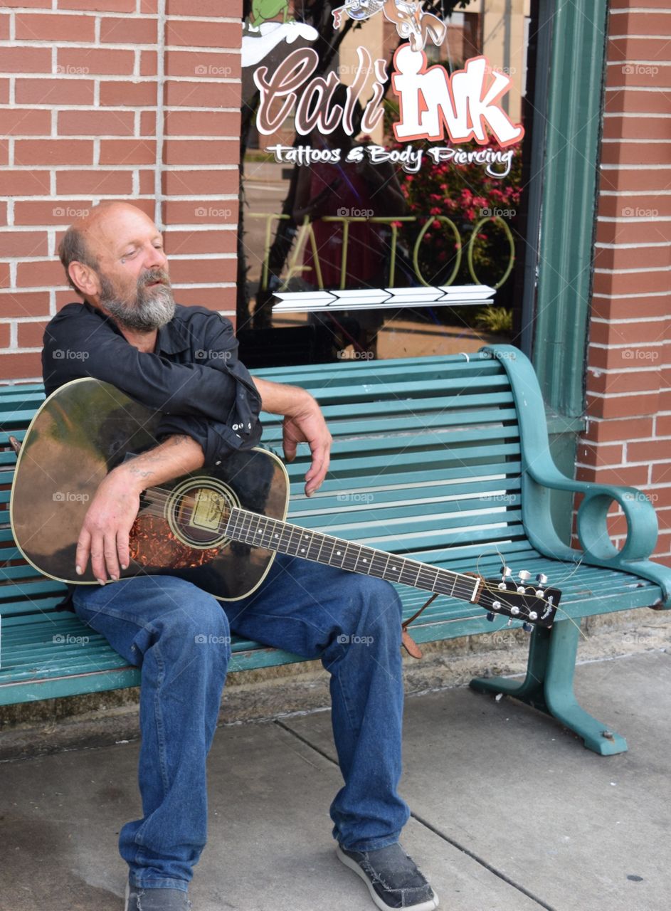 Man sitting on bench with guitar