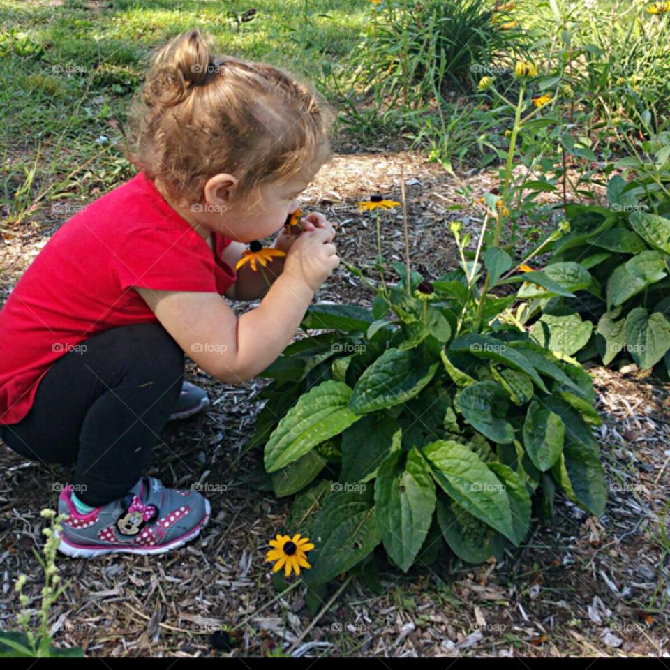 Two year old stopped playing to smell the flowers.  We can learn from her.  