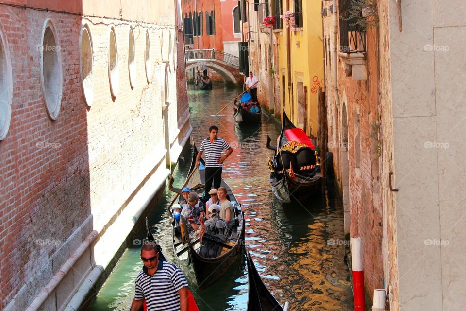 People riding gondola in Venice through water canals 