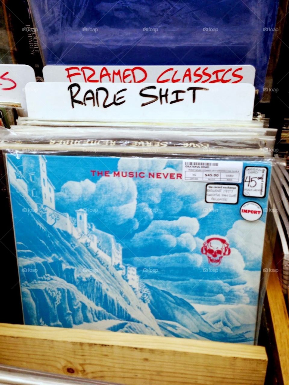 A photograph taken in a record store that has a category called "Rare Shit". The album shown is The Music Never Stopped by the Greatful Dead