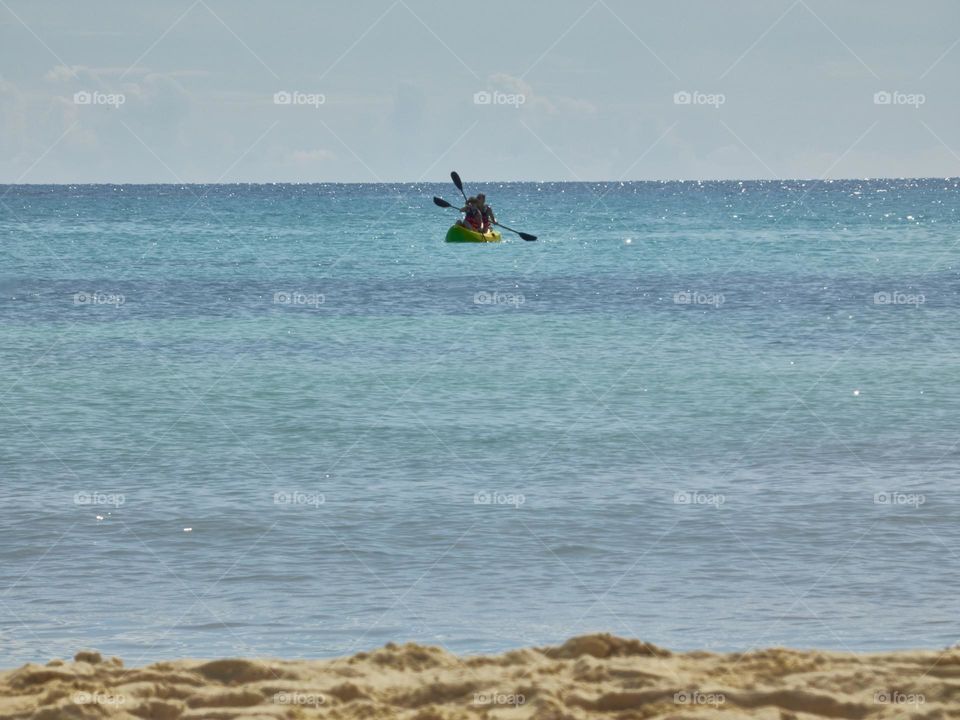 two people practicing canoeing in the caribbean sea on the shores of the beach