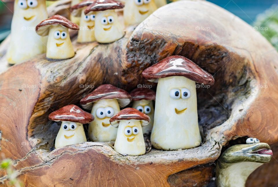 Small decorative mushrooms with eyes and a cheerful smile in the artificial bark of a tree on a spring sunny day on the island of Capri, Italy, close-up side view.