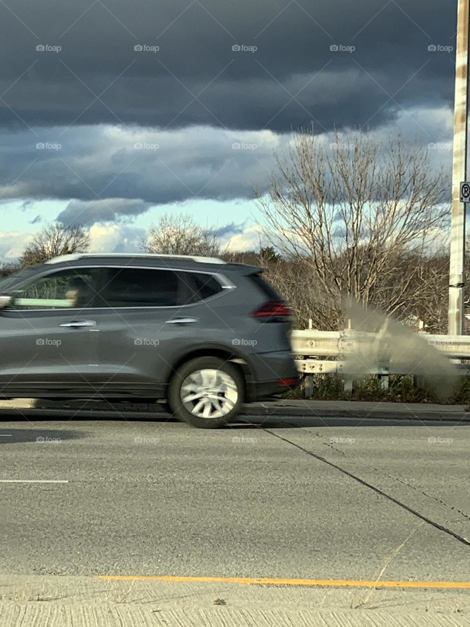 Car driving away from stormy sky