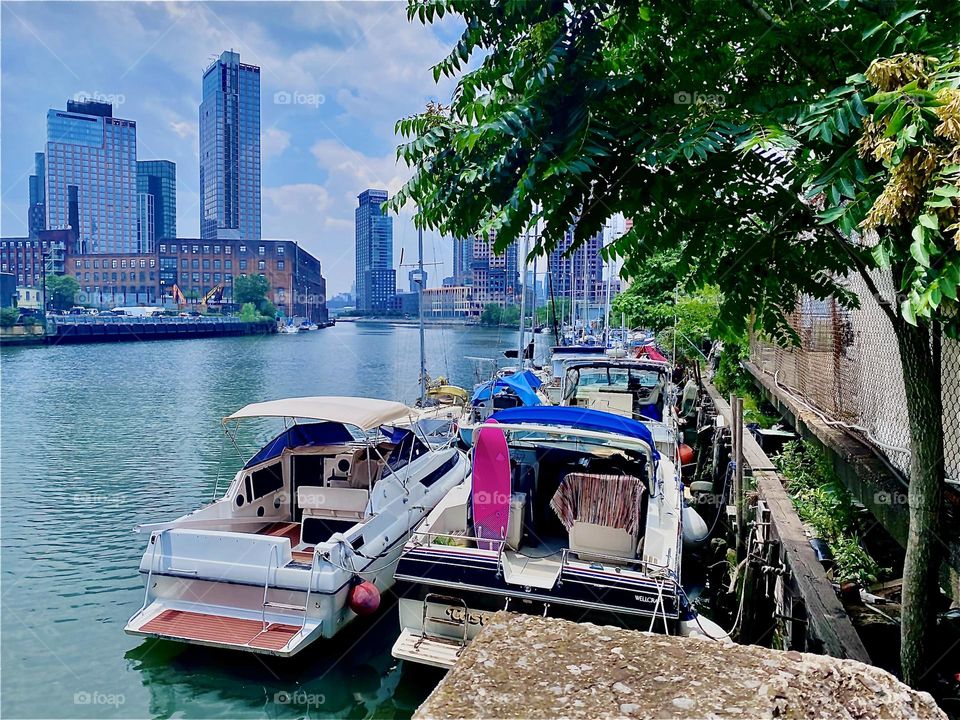This is the spectacular view of NYC that can be enjoyed from the parking lot beneath the „Pulaski Bridge“ at „Newtown Creek“ where all sorts of boats are tied to the shore giving it a vibrant beautiful look. 2023. Hypnotic Productions