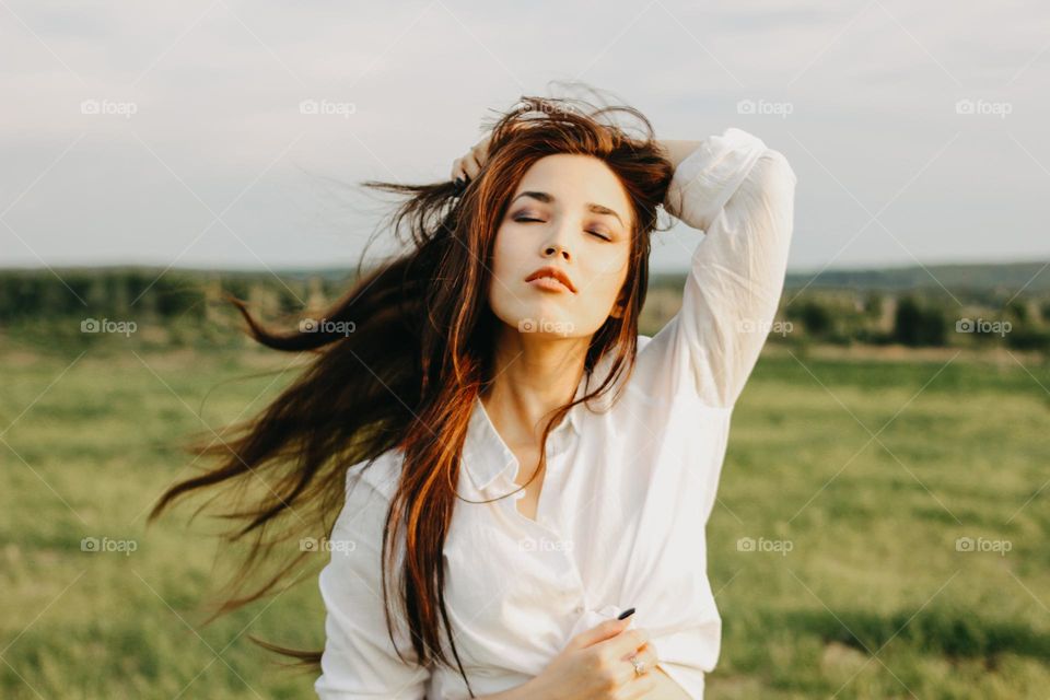 Close up portrait of beautiful carefree long hair girl in white clothes in nature field. Sensitivity to nature concept
