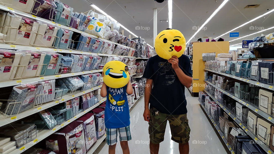 Emoji Family- A father and son playfully sporting emoji pillows over their faces.