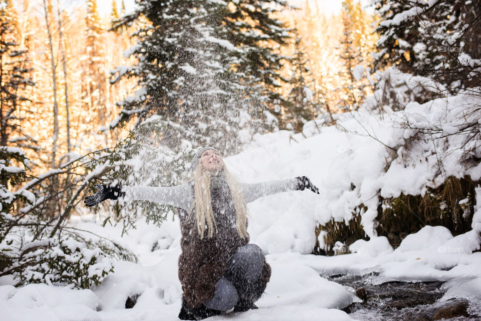 Woman wearing worm clothing splashing snow