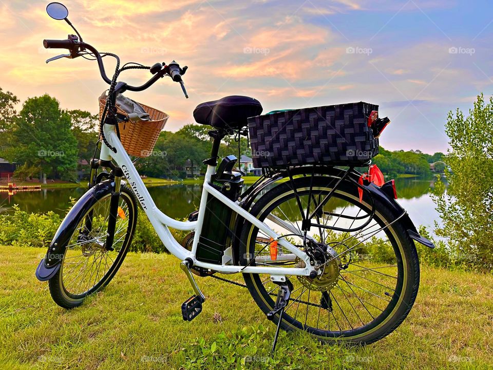 One Lonely Bicycle - A cool bicycle is parked on the grass in front of a calm lake during a fantastic sunset