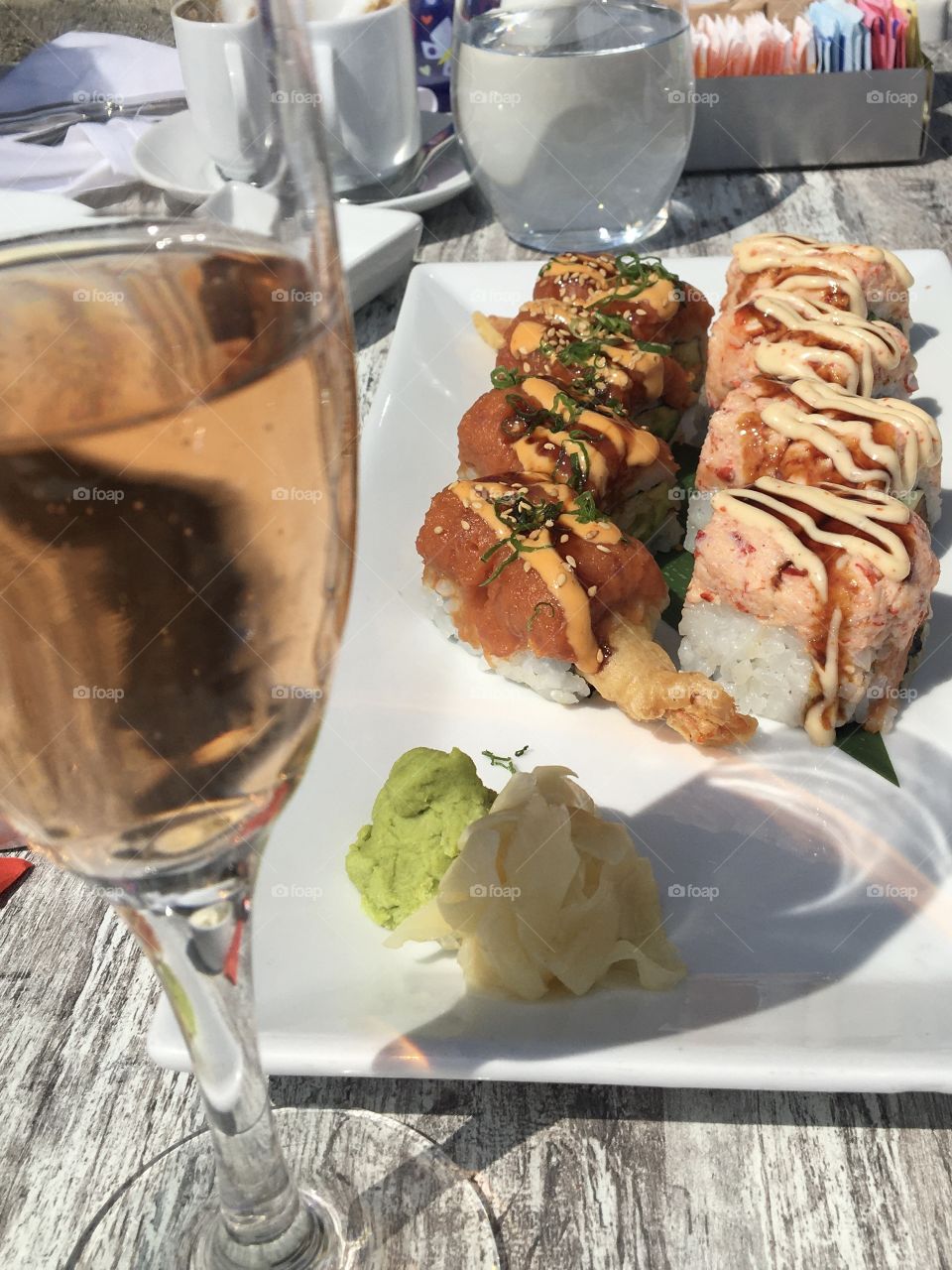 Plate of shrimp and lobster sushi with wasabi, ginger and a glass of sparkling rosé 