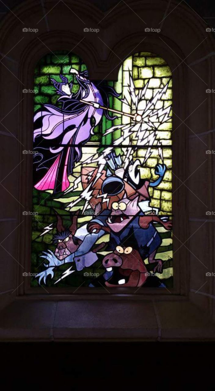 Disney land Paris / Euro Disneys 

one of Sleeping beauty castles 
stain glass window

Maleficent (/məˈlɛfɪsənt/ or /məˈlɪfɪsənt/) is the main antagonist of Walt Disney's 1959 film Sleeping Beauty. She is characterized as the "Mistress of All Evil" who, after not being invited to a christening, curses the infant Princess Aurora to "prick her finger on the spindle of a spinning wheel and die" before the sun sets on Aurora's sixteenth birthday. 
(series available  )

Sleeping Beauty Castle is the fairy tale structure castle at the center of Disneyland Park, Hong Kong Disneyland and Disneyland Paris. It is based on the late-19th century Neuschwanstein Castle in Bavaria, Germany,with some French inspirations (especially Notre Dame de Paris and the Hospices de Beaune).