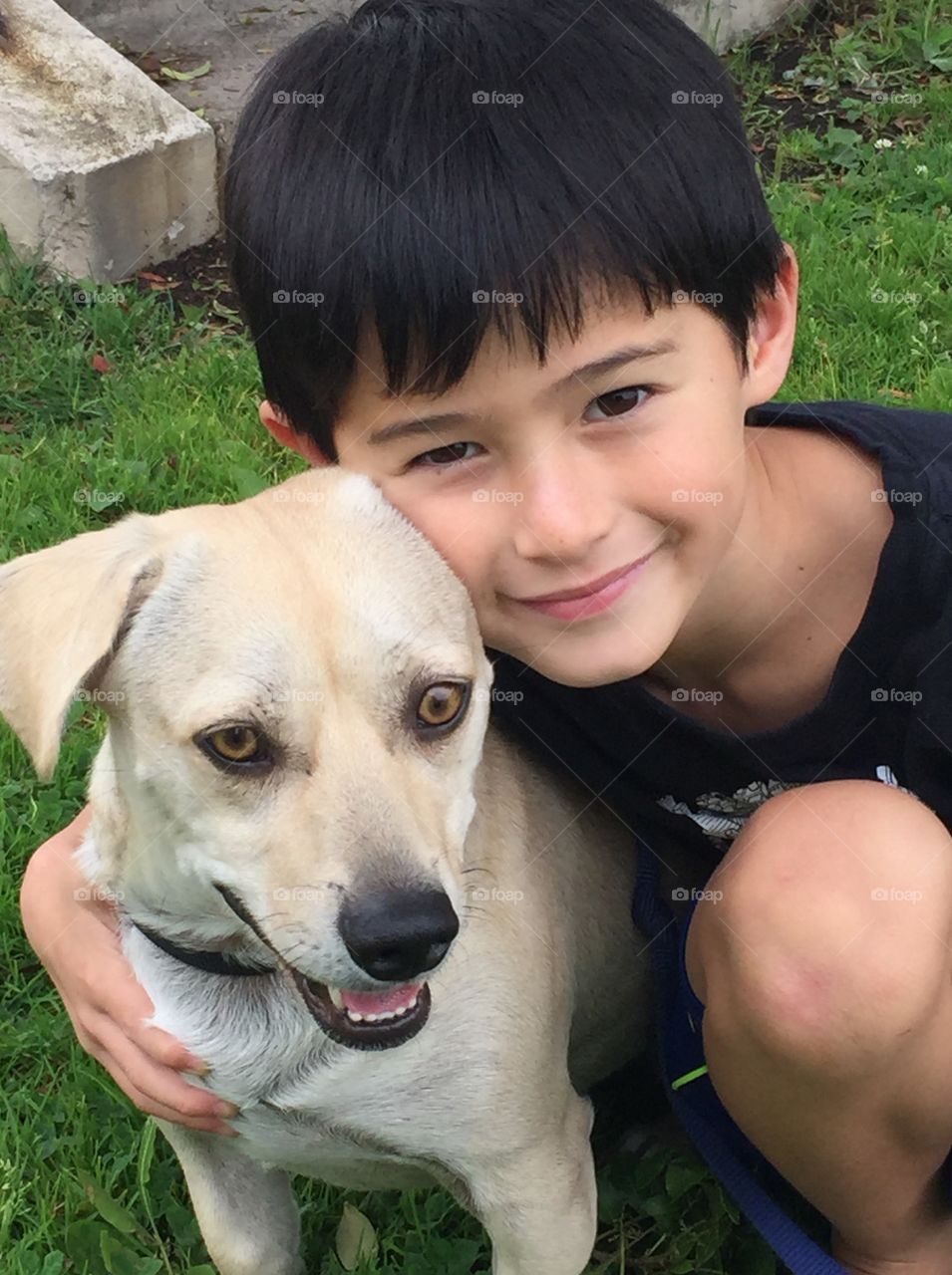 Handsome boy on grass looking at camera with dog