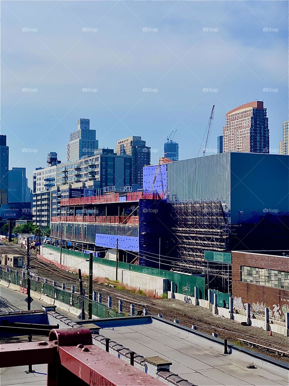 This cityscape of LIC, Queens and behind it „Manhattan“ and view of the train tracks was seen from the staircase leading up to the „Pulaski Bridge“ on a hot, humid and sunny afternoon in September 2023. Hypnotic Productions