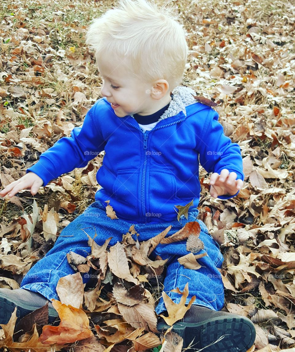 Happy boy sitting on autumn leaf