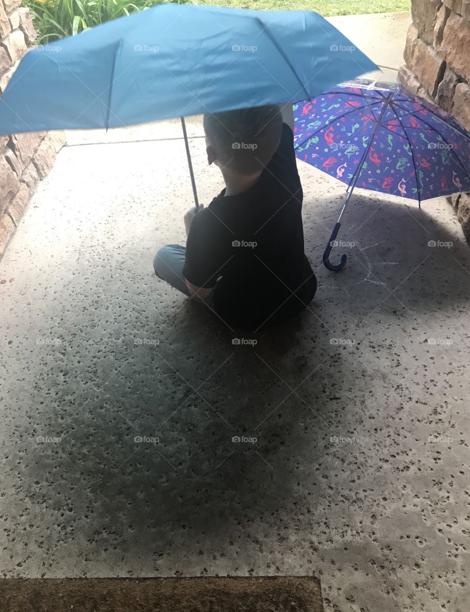 Little boy holding and umbrella keeping dry from the rain 