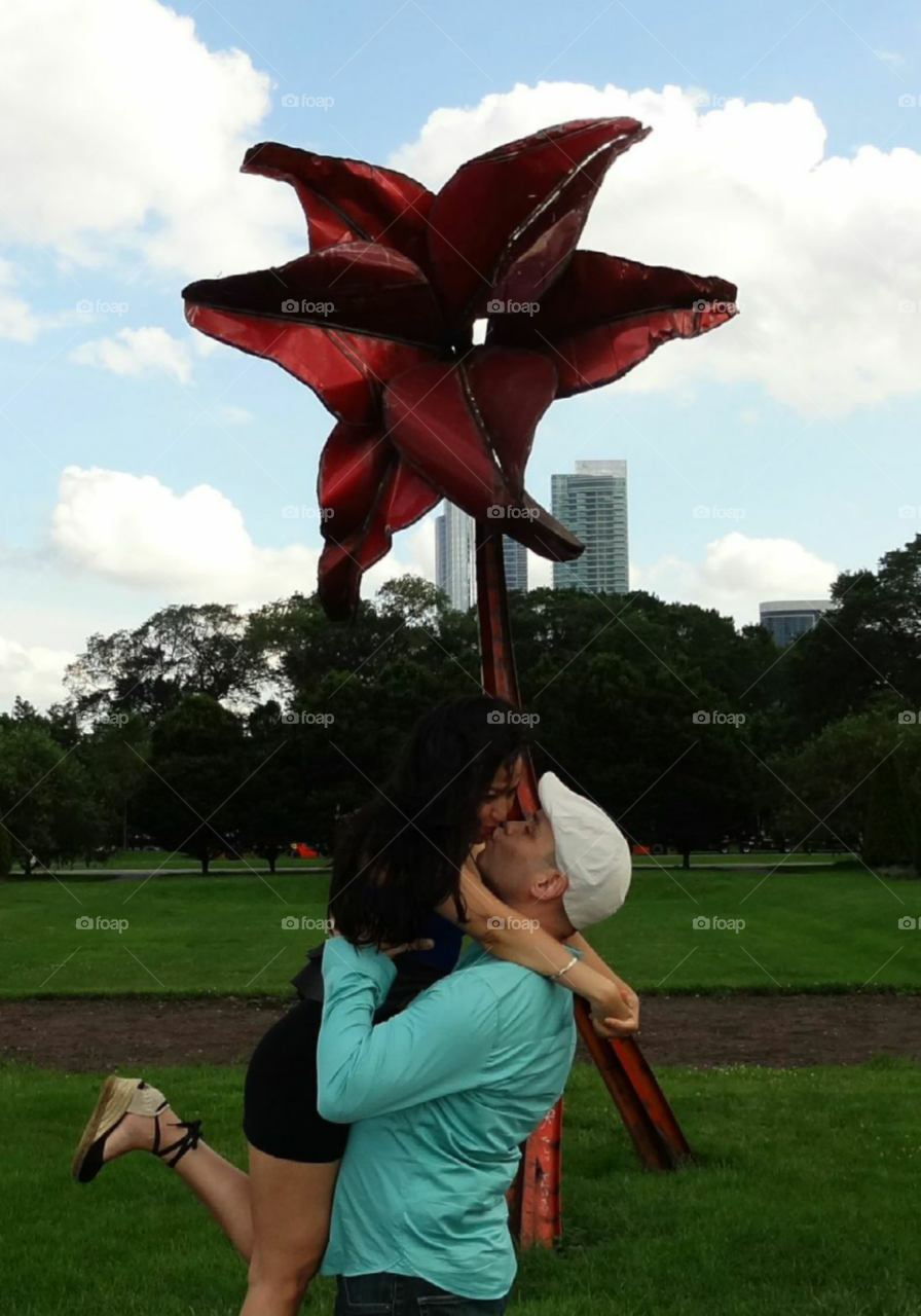 kissing under big metal flower. timer camera for pre wedding photo shoot 