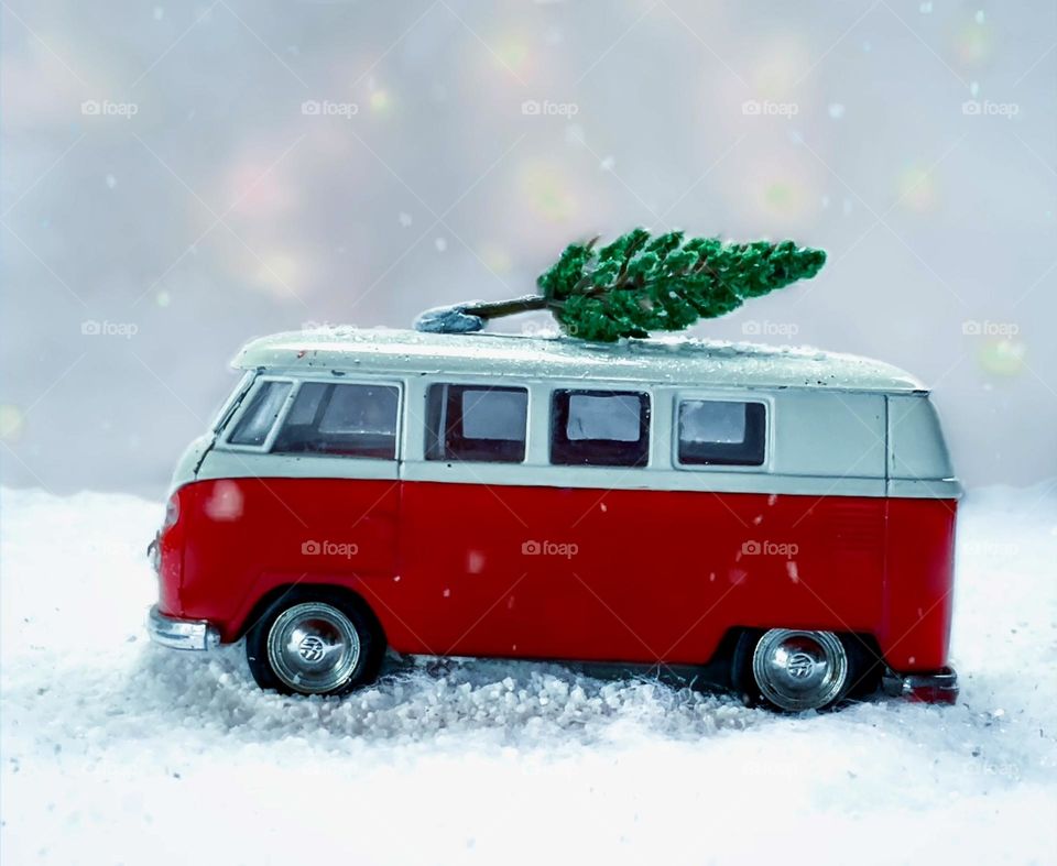 A toy camper van in the fake snow, with lights in the background 