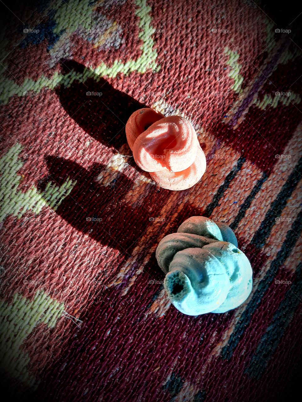 two pastel meringues on oriental rug with long shadows