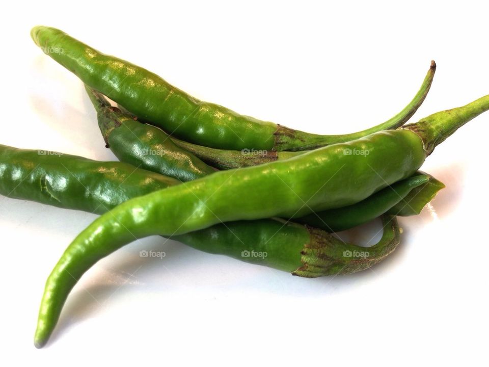 Green chilies on white background
